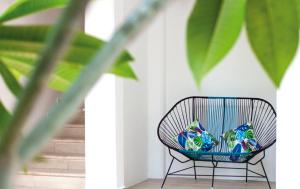 a black rattan chair with colorful pillows on it at Albatros Suites by Bedsfriends in Cozumel