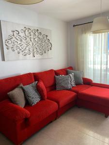un sofá rojo sentado en una sala de estar en Tenerife apartamento Sun Beach & Relax, en Puertito de Güímar