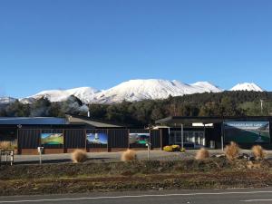 a building with snow covered mountains in the background at Tongariro Holiday Park in National Park