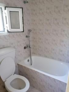 a bathroom with a white toilet and a bath tub at Faneromeni Two bed Apartment B (1st Floor) in Zakynthos