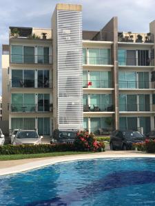 een groot appartementencomplex met een zwembad ervoor bij Departamento Acapulco Diamante in Acapulco