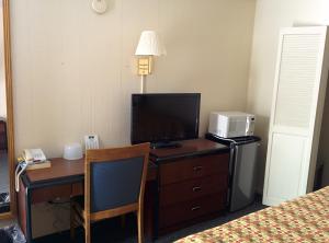 a hotel room with a desk with a television and a bed at Economy Inn Toledo-Perrysburg in Perrysburg