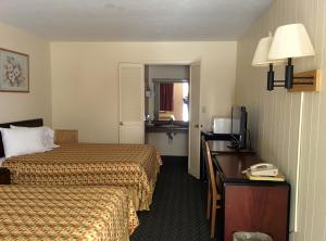 a hotel room with two beds and a desk with a telephone at Economy Inn Toledo-Perrysburg in Perrysburg