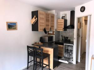 eine kleine Küche mit einer Theke und Stühlen darin in der Unterkunft Studio chaleureux à la Foux D’Allos in Allos