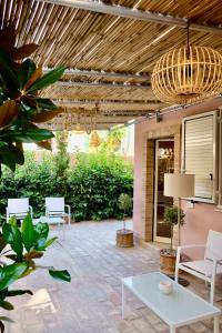a patio with white chairs and a chandelier at B&B Don Savè in Marina di Schiavonea