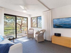 um quarto com uma cama, cadeiras e janelas em Intrepid 1 3 Intrepid Close Amazing views of Shoal Bay only 100m from the Beach em Shoal Bay