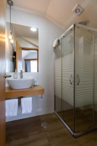 a bathroom with a sink and a glass shower at Hotel Arcanjo in Rosário-Lagoa
