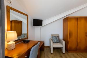 Zimmer mit einem Schreibtisch, einem Spiegel und einem Stuhl in der Unterkunft Hotel Arcanjo in Rosário-Lagoa