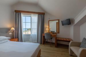 a hotel room with a bed and a desk and a window at Hotel Arcanjo in Rosário-Lagoa