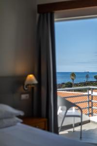 a room with a bed and a view of the ocean at Hotel Arcanjo in Rosário-Lagoa