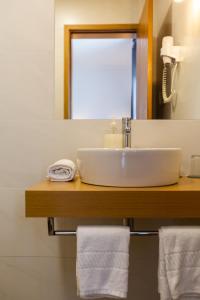 a bathroom with a sink and a mirror and towels at Hotel Arcanjo in Rosário-Lagoa