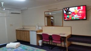 a room with a kitchen with a tv on the wall at Sandcastle Motel Tin Can Bay in Tin Can Bay