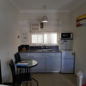 a kitchen with a table and a sink and a microwave at Motel Lodge in Rockhampton