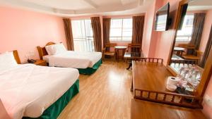 a hotel room with two beds and a table at A.A. Pattaya Golden Beach Hotel in Pattaya Central