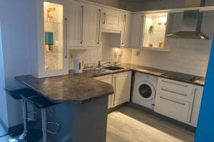 a kitchen with white cabinets and a washing machine at Seaview House in Aberdeen