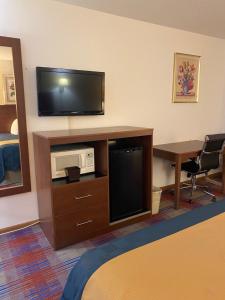 a hotel room with a television and a desk with a table at Americas Best Value Inn Champaign in Champaign