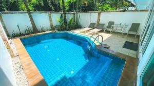 una piscina con mesa y sillas junto a ella en Hidden Palm Pool Villas, en Norte de Pattaya