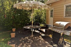 a patio with a grill and a table with an umbrella at The Bungalow in Grand Forks