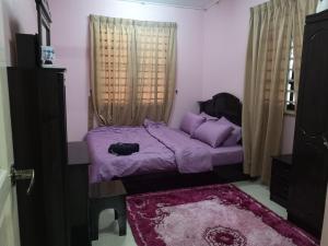 a small bedroom with a purple bed and a window at RH Homestay Berhawa Dingin in Kota Bharu