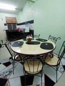 a table and chairs in a room with a kitchen at RH Homestay Berhawa Dingin in Kota Bharu