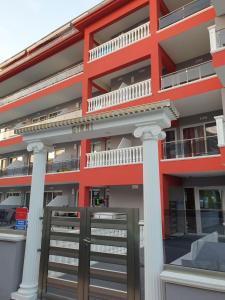 an apartment building with a red facade and white columns at M & M Red Luxury in Paralia Katerinis