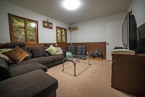 Una sala de estar con un sofá y un televisor. en The Jungle House - Hakuba, en Hakuba