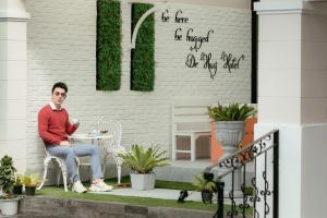 a man sitting on a chair on a patio at De Hug Hotel & Residence in Chiang Rai