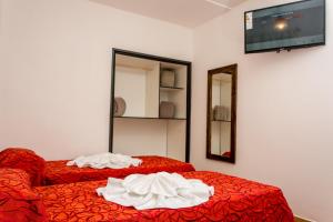 2 Betten mit roter Bettwäsche in einem Zimmer mit einem TV in der Unterkunft Ns Hotel in Termas de Río Hondo