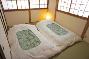 a small bedroom with two beds with white sheets at Gion Rokudo in Kyoto