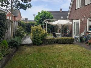 un patio trasero con sombrilla, mesa y sillas en Logies bij Wandelpad te Holten, en Holten