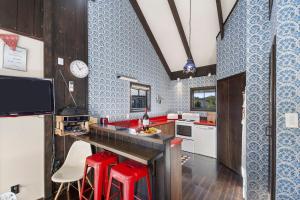 a kitchen with red stools and blue and white tiles at Chalet Mahuta - Five Mile Bay Holiday Home in Waitahanui