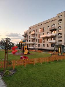 einen Spielplatz vor einem großen Gebäude in der Unterkunft Grey Residence Apartament in Târgu Mureș