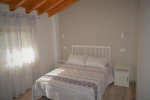 a white bedroom with a bed and a window at CASA SOLORGA - apartamentos rurales in San Miguel de Meruelo