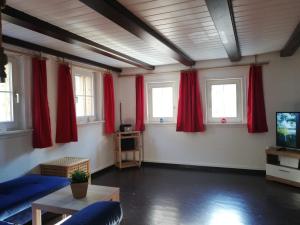 a living room with red curtains and a tv at Häusle an der Hüle in Hohenstein