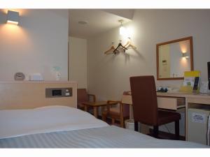 奄美市にある奄美ポートタワーホテルのベッド、テーブル、椅子が備わるホテルルームです。