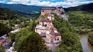a castle on the side of a mountain next to a river at MyMara , Apartmán Ivadella in Bešeňová