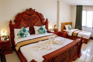 a bedroom with a large wooden bed with towels on it at Kampong Thom Palace Hotel in Kompong Thom