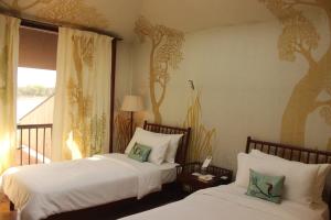 two beds in a room with trees on the wall at RAAS Chhatrasagar, Nimaj, District Pali in Pāli