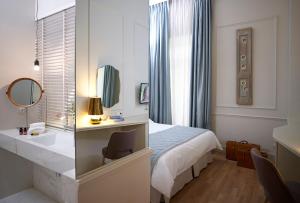 a bedroom with a bed and a desk and a mirror at Marpessa Hotel & Spa in Agrinion