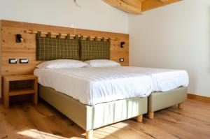 a bedroom with a large bed with white sheets at Bioagritur La Casa dei Trajeri in Fai della Paganella