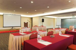 a conference room with tables and chairs and a screen at Hotel Primera Suite Cyberjaya in Cyberjaya