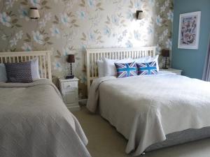 1 dormitorio con 2 camas y papel pintado con motivos florales en Old Borough Arms en Rye