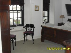 a bedroom with a bed and a chair and windows at The Old Library & Lodge in Arisaig