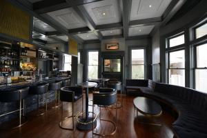 a bar with black stools and tables and windows at Hotel Ella in Austin
