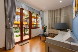 ein Wohnzimmer mit einem weißen Sofa und einem TV in der Unterkunft Mộc Châu Eco Garden Resort in Mộc Châu