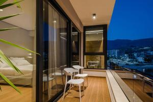 a bedroom with a balcony with a bed and stools at Rea Boutique Hotel in Himare