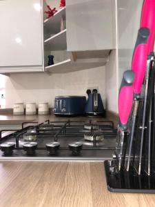 La cocina está equipada con fogones y utensilios de color rosa. en Blackpool Abode - Palatine House en Blackpool