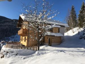 a log cabin in the snow with a tree at Gut Schablberg in Radstadt