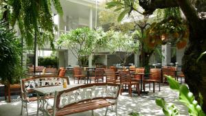 un restaurante con mesas, sillas y árboles en Trang Hotel Bangkok - SHA Plus en Bangkok