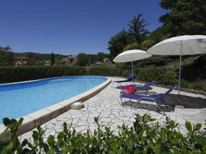 two chairs and umbrellas next to a swimming pool at La Palombe in Octon